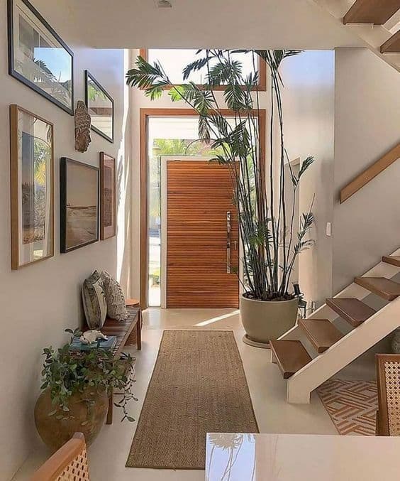 Entrance foyer with a wooden door, runner rug and tall plants